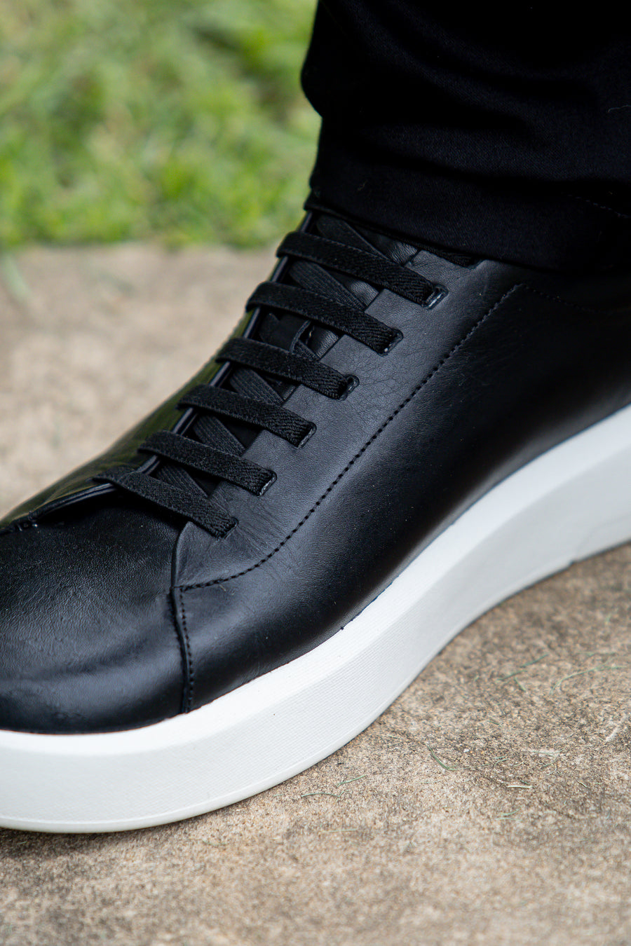 Detalhe do tênis casual preto e branco, com cadarço preto e solado branco