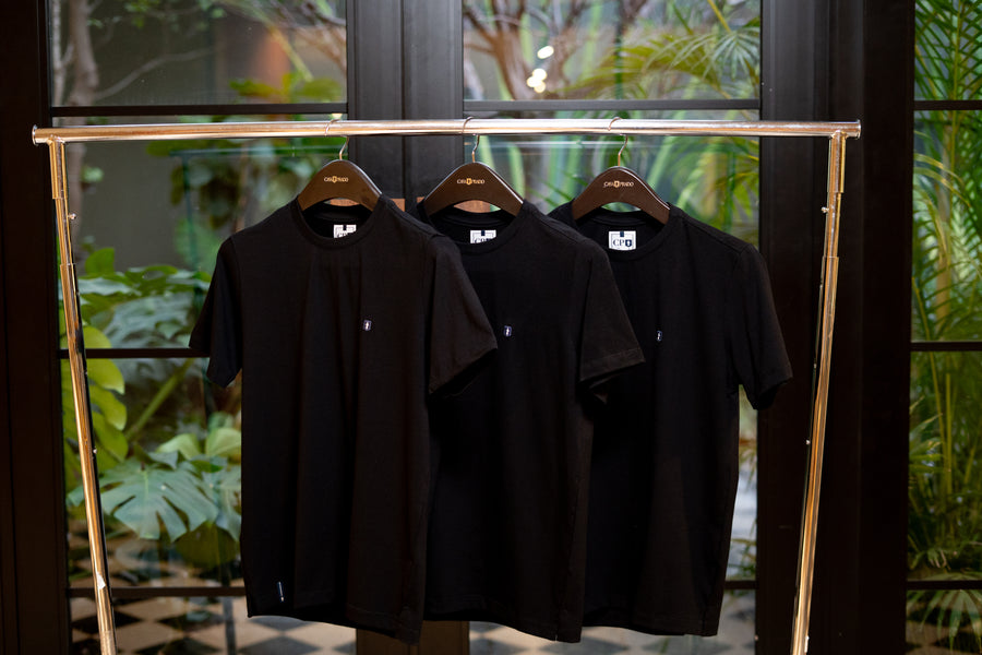 Kit de três camisetas premium pretas da Casa Prado penduradas em arara